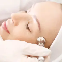 Zabieg oxybrazji na twarz. Kosmetolog w rękawiczce wykonuje delikatny peeling skóry.