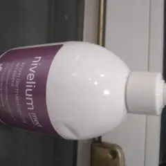 Biała butelka z pompką, na której widnieje napis "nivelium med krem dermatologiczny".
