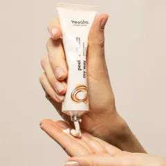 Dłonie trzymają tubkę z kosmetykiem. Z tubki na dłoń wyciska się kremowy produkt, który działa jak keratolityk, złuszczając naskórek.
