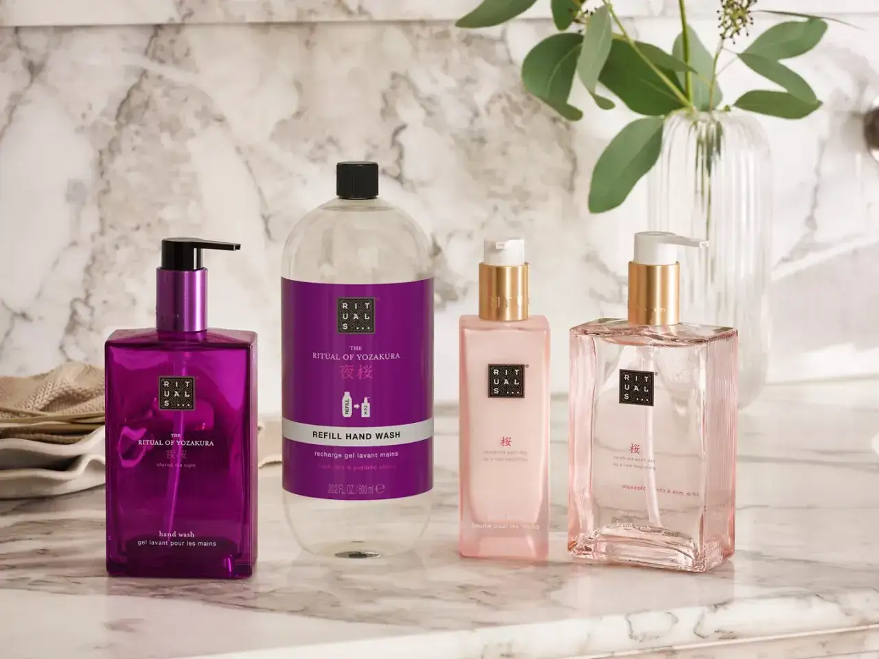 Rituals co to za marka? Zestaw kosmetyków Rituals of Yozakura: fioletowy żel do rąk, duży wkład do mydła, różowy balsam do rąk i różowe mydło.